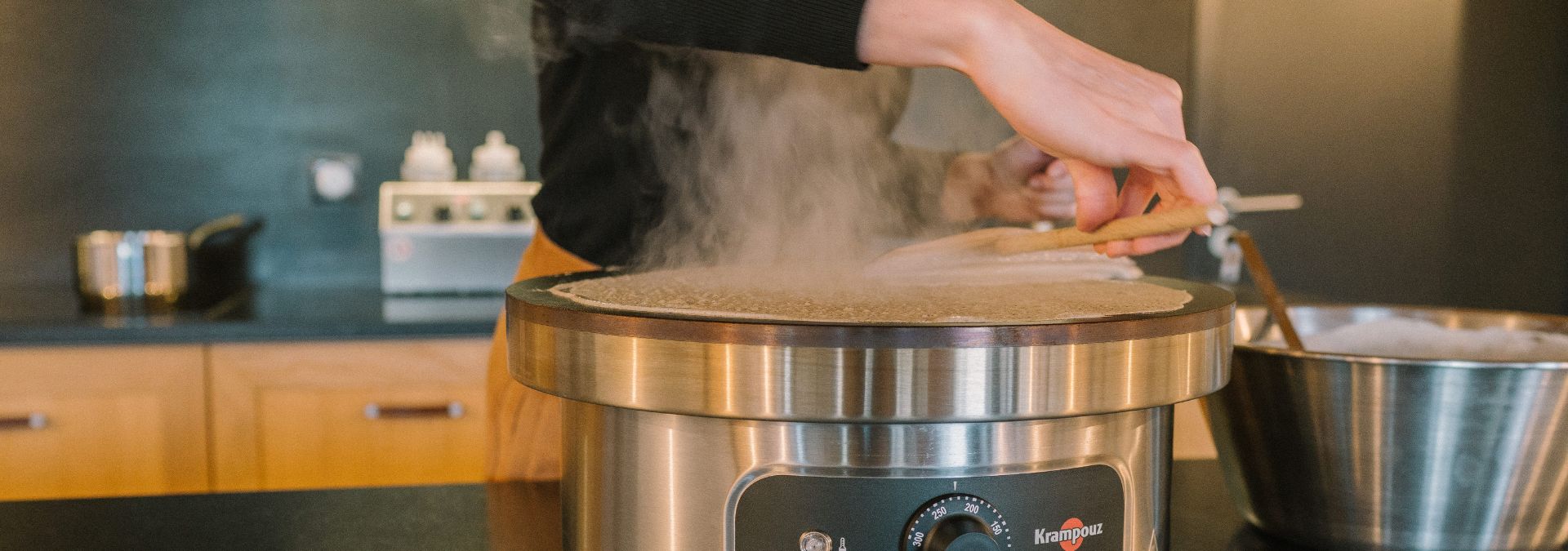 Gros plan sur la main d’une crêpière tournant une crêpe sur un billig.