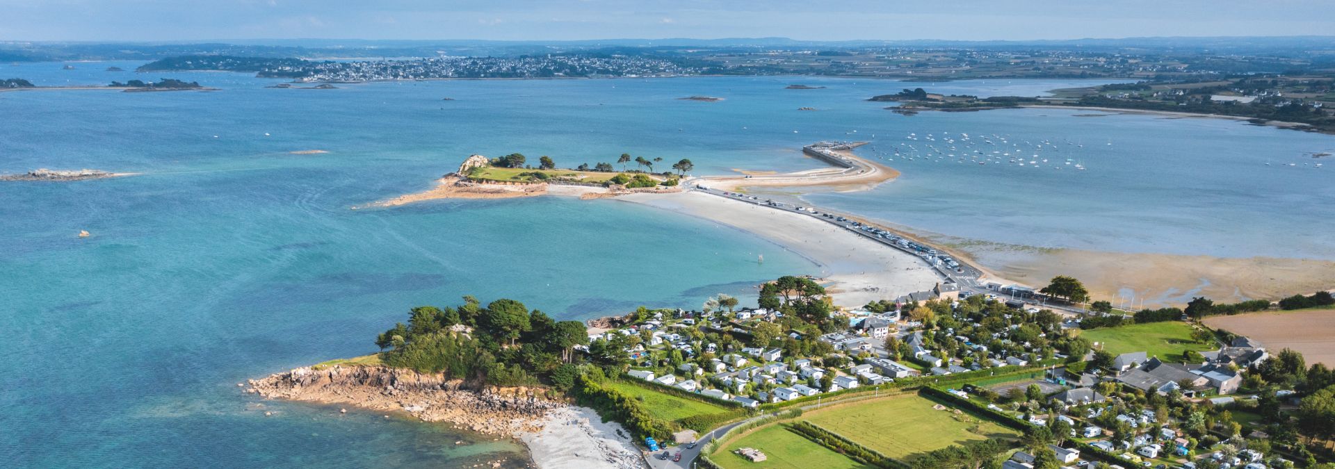 Vue aérienne de la côte de Saint-Pol-de-Léon avec plages, îlots et camping en bord de mer.