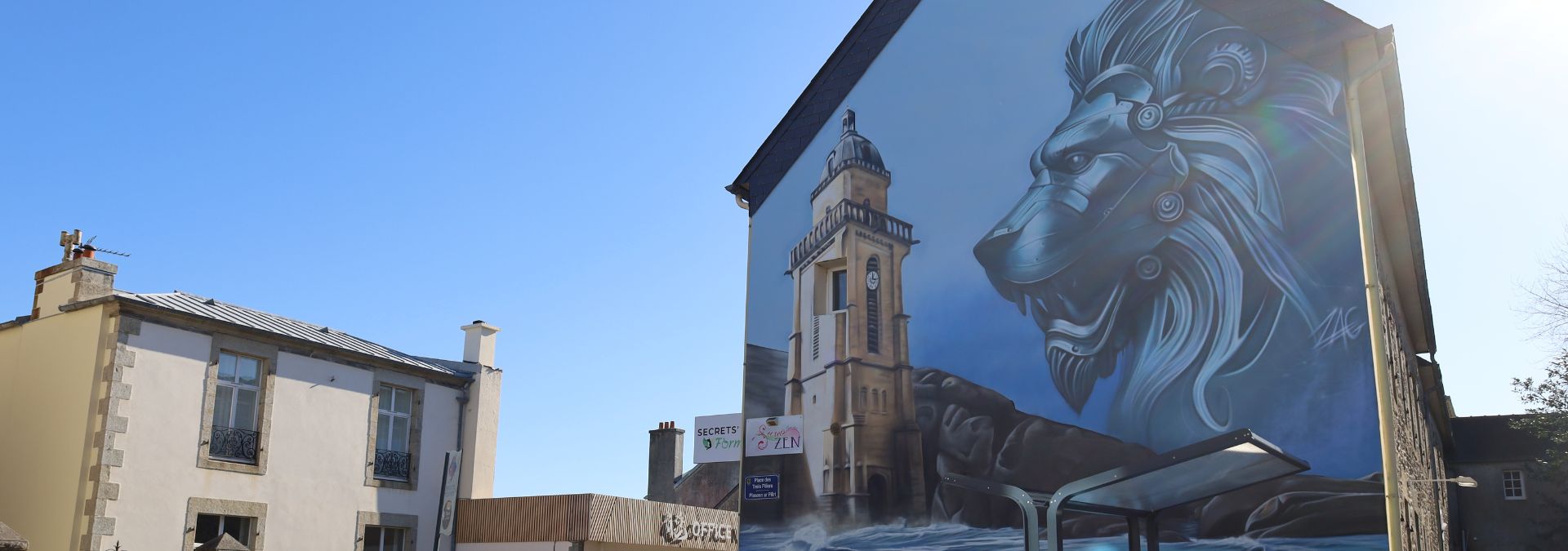 Fresque murale de ZAG à Lesneven avec un lion mécanique et un phare breton.