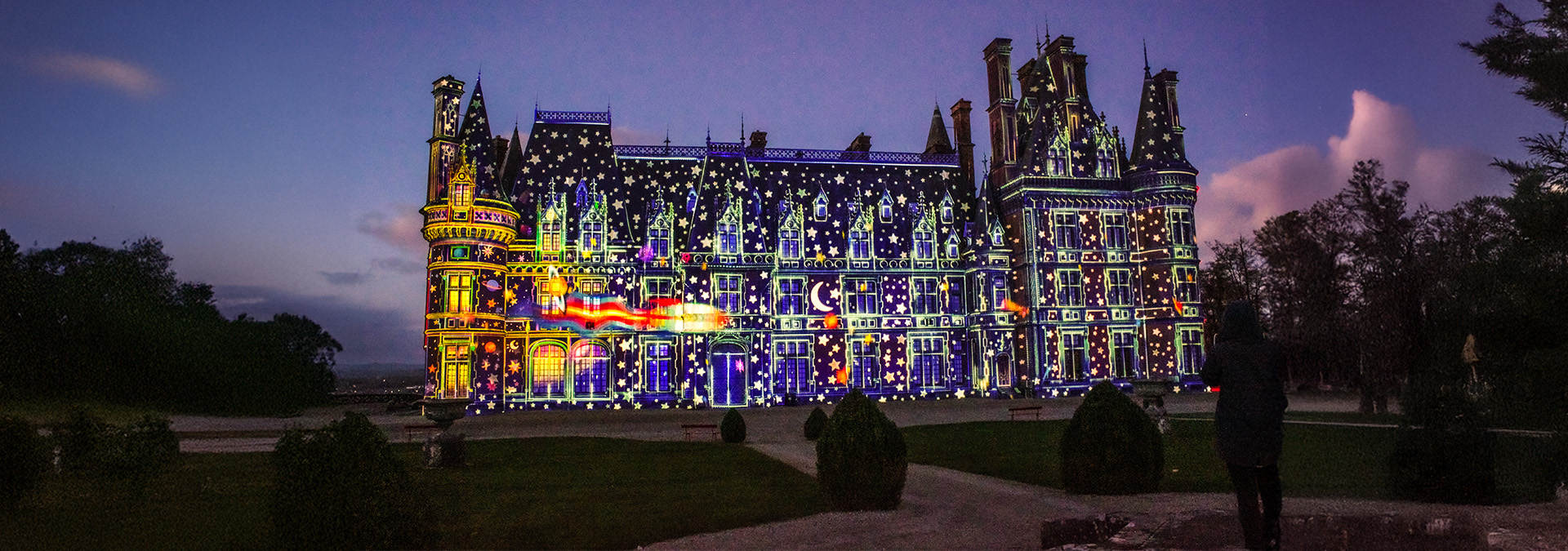 Façade illuminée du château de Trévarez ornée de projections lumineuses festives à la nuit tombée.