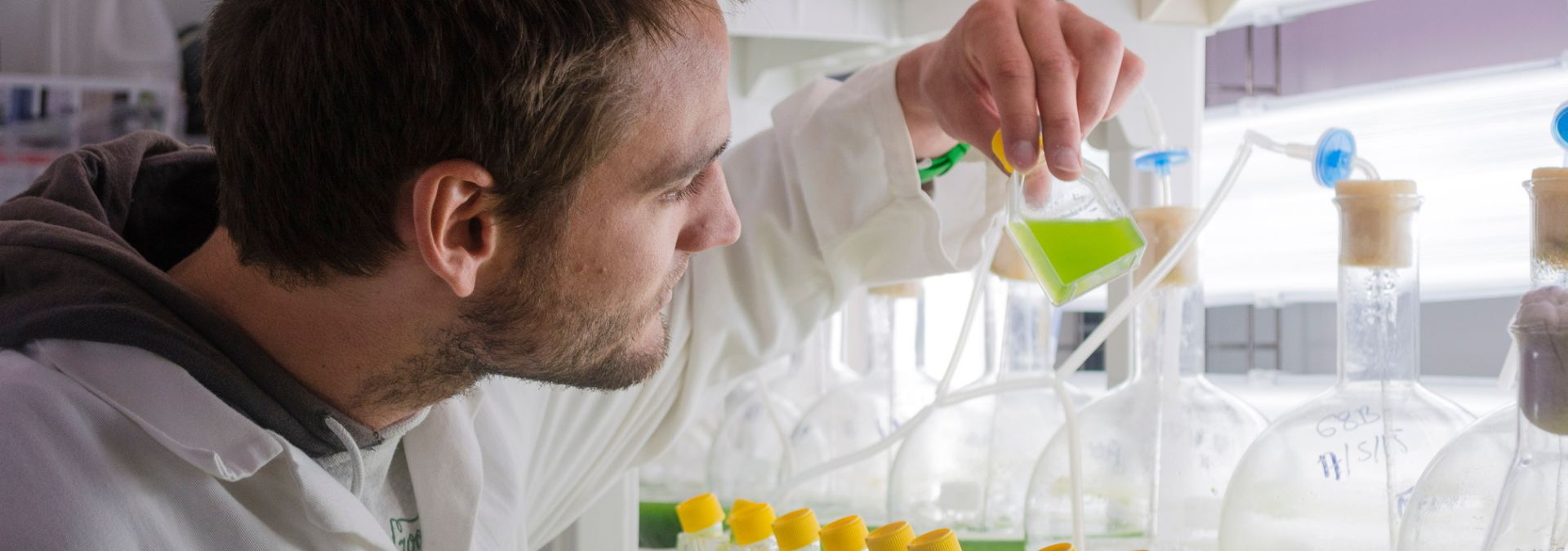 Chercheur manipulant des flacons contenant des solutions en laboratoire scientifique.