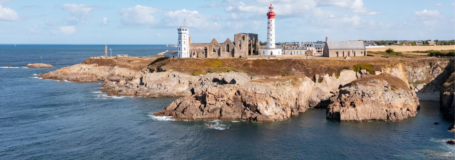 Phare et ruines de l’abbaye de la Pointe de Saint-Mathieu sur une côte rocheuse face à l’océan.