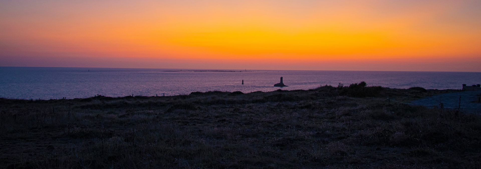Coucher de soleil sur l’océan avec ciel orange et silhouette de balise au large