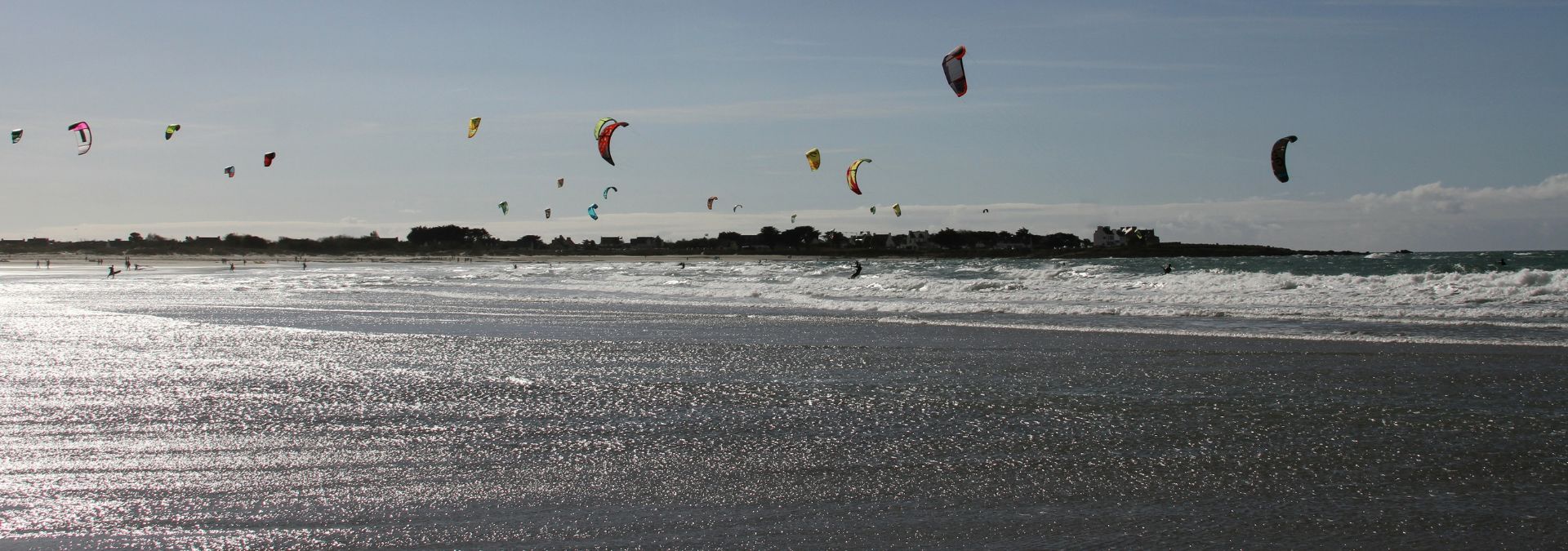 Ailes de kitesurf au-dessus de la plage de Pors Carn avec vagues et océan à Penmarc’h.
