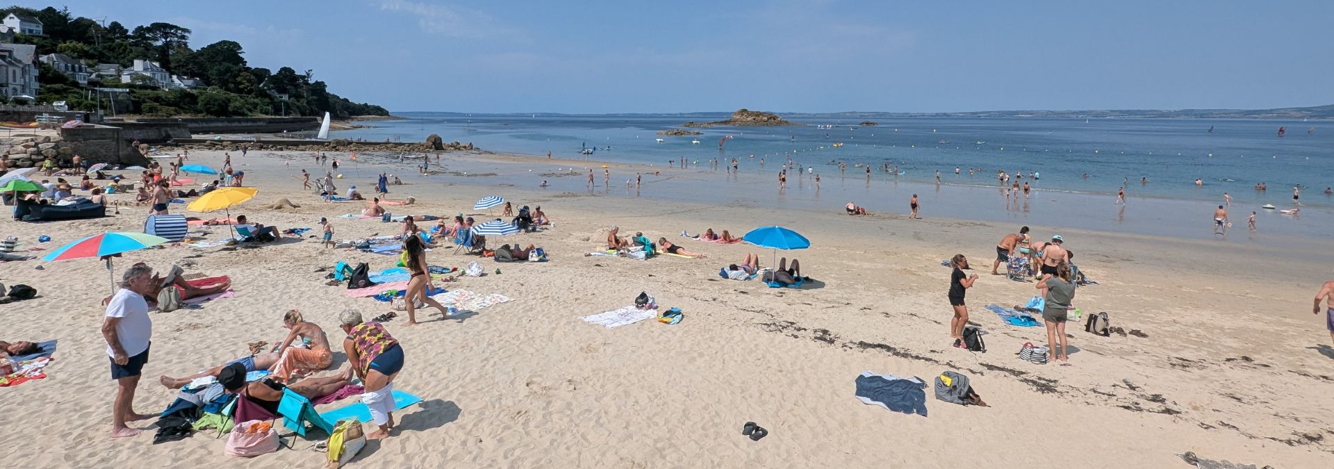 Vacanciers installés sur la plage des Sables Blancs à Douarnenez face à une mer calme.