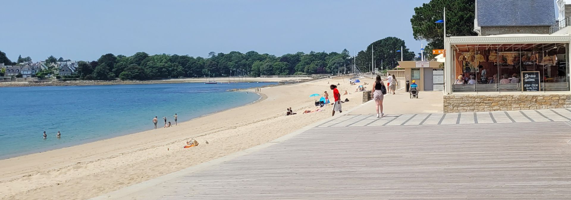 Vue sur la plage du Trez à Bénodet avec promenade en bois, sable fin et baigneurs.