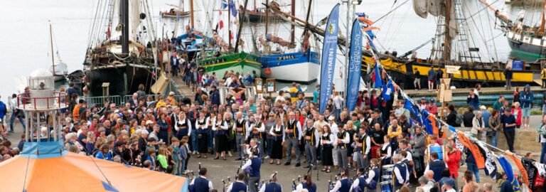 Un bagad se produit devant une foule rassemblée sur le port de Douarnenez, entouré de vieux gréements lors des Fêtes maritimes du Finistère.