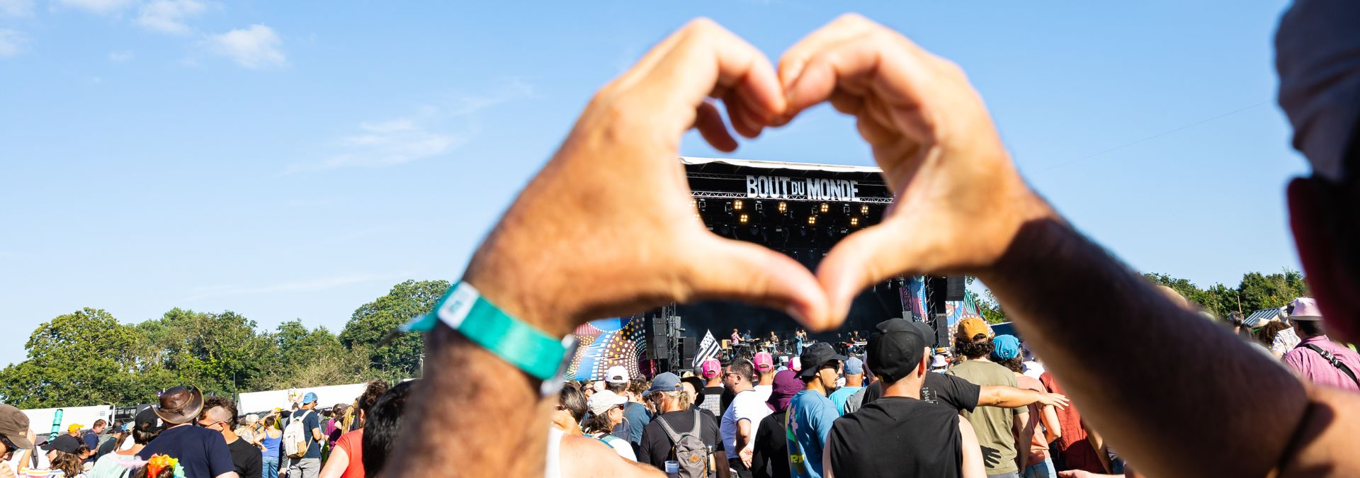 Un festivalier forme un cœur avec ses mains devant la scène du Festival du Bout du Monde dans le Finistère.